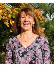 Photograph of Woman Smiling, wearing purple printed shirt.