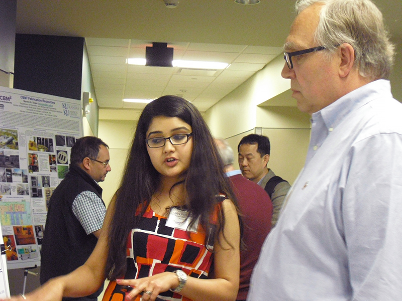 Two individuals discussing a research poster, with one person gesturing towards it.