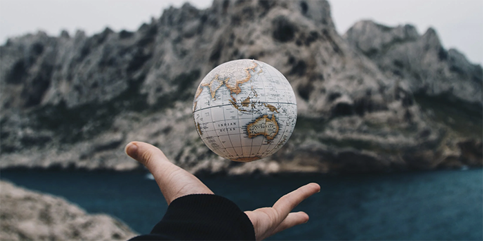 Illustration with hand tossing small globe. Credit: Pexels