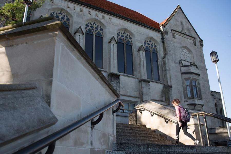 A student walks up the Watson Library steps at the University of Kansas