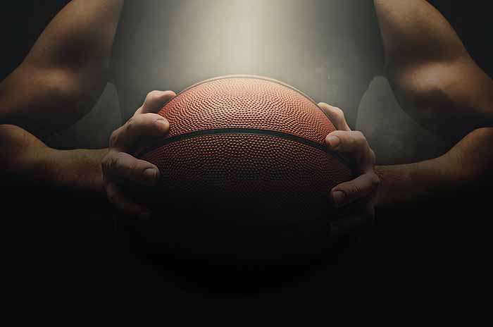 Cropped image of individual holding basketball.