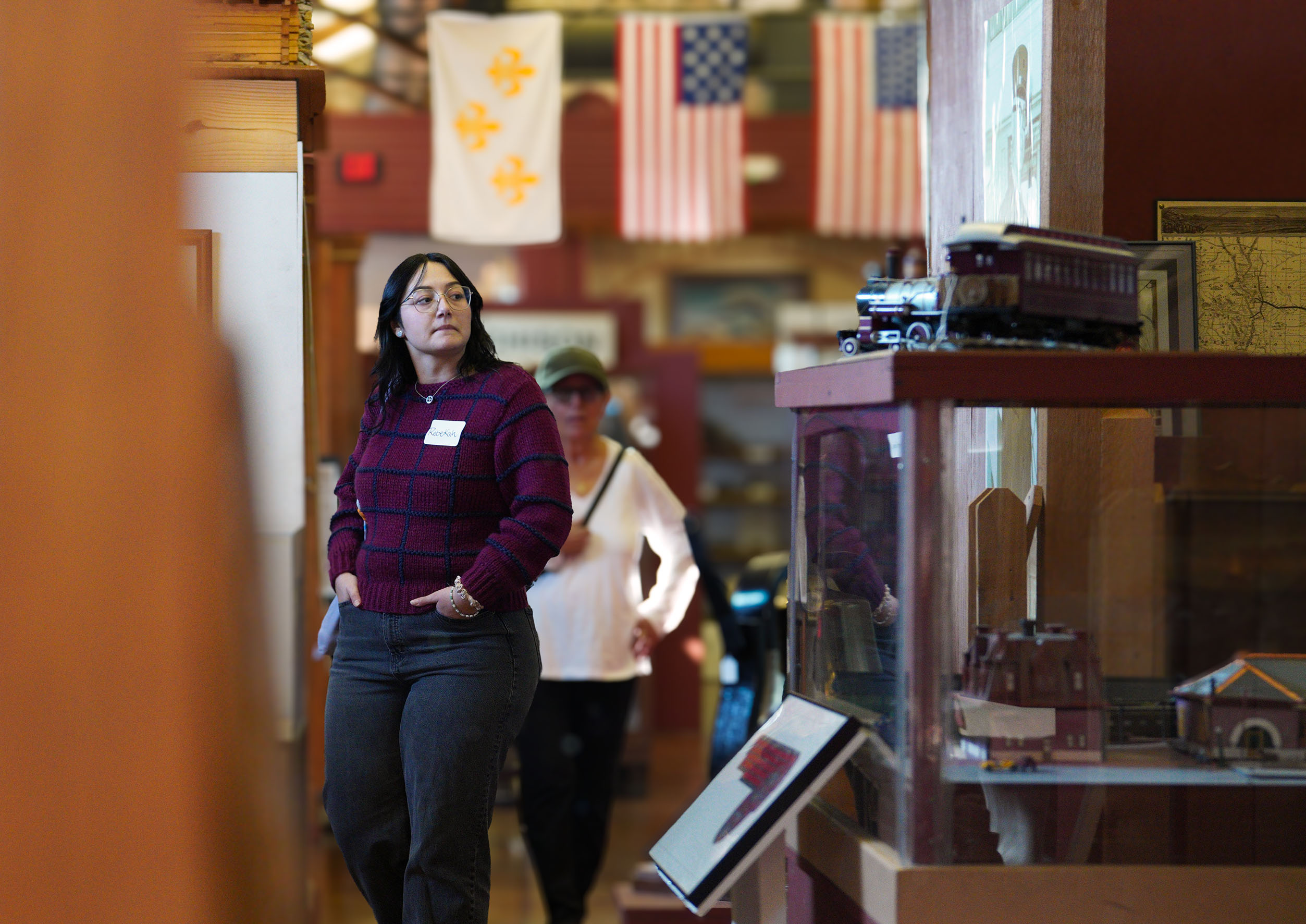 Two guests walk through the exhibits at the Santa Fe Depot museum as a model train sits in the foreground.