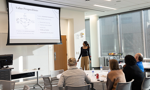 A student presents their business pitch to a panel of judges in a competition.