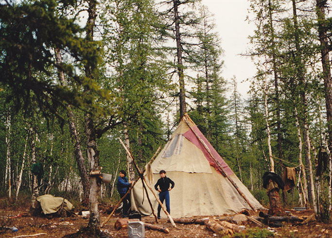 A pair of reindeer herders set up teepees in a forest