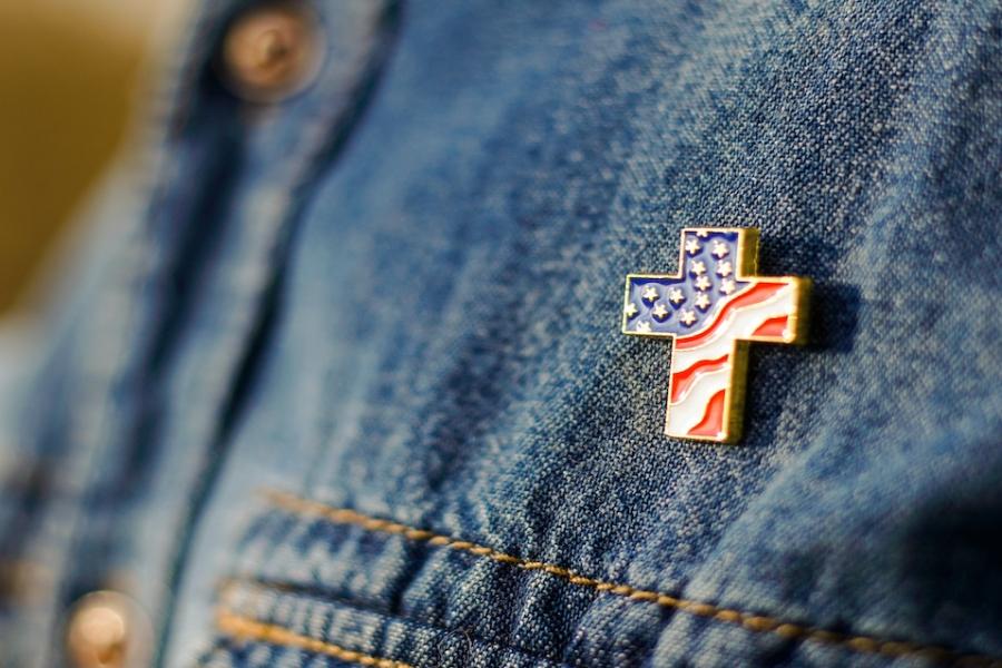 A person wearing a cross pin that features a pattern of the American flag.