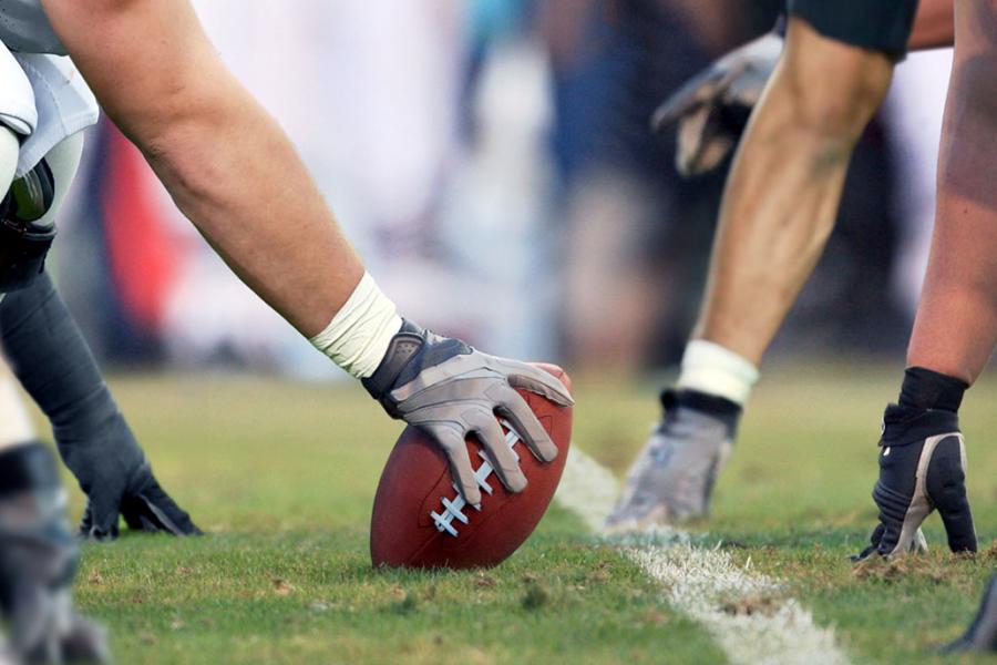 An image of football players' hands touching the ground as they line up for a play.