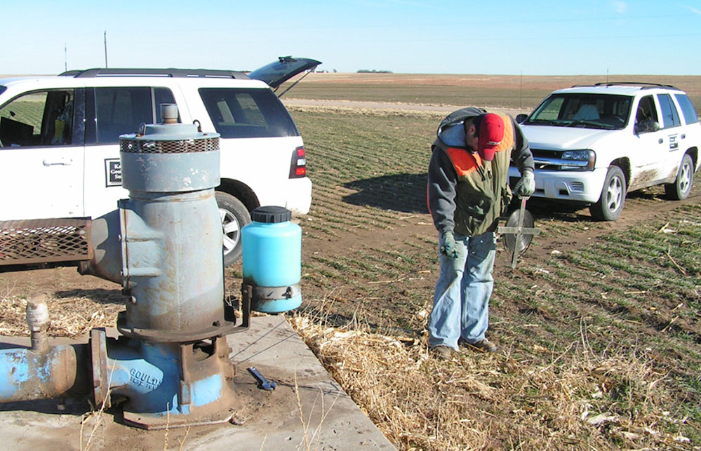 A Kansas Geological Survey crew member takes measurement near a field.