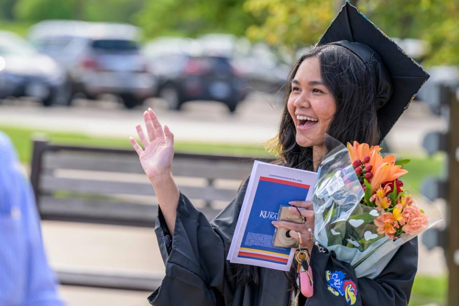 Olivia Sourivong waves to family and friends at the KU School of Social Welfare graduation ceremony