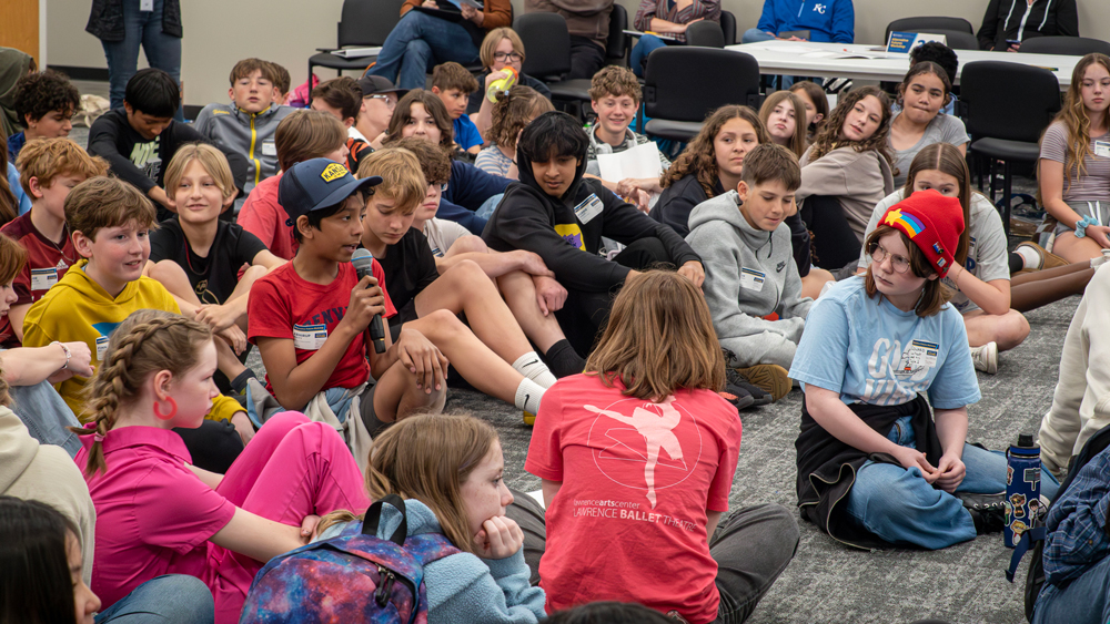 Middle school boy speaking on a mic in front of the group