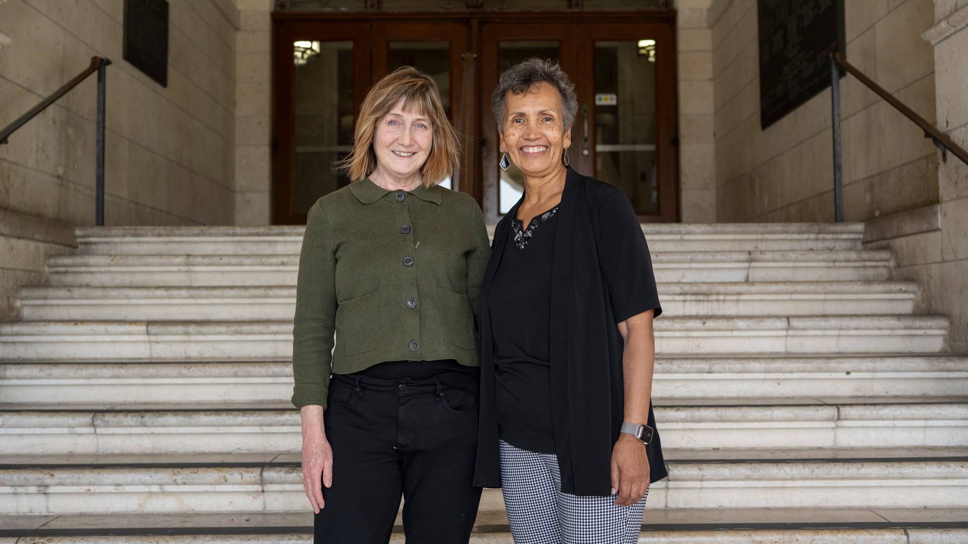 Carol Smith and Lorraine Haricombe pose in front of the steps at the University of Texas' Main Building.