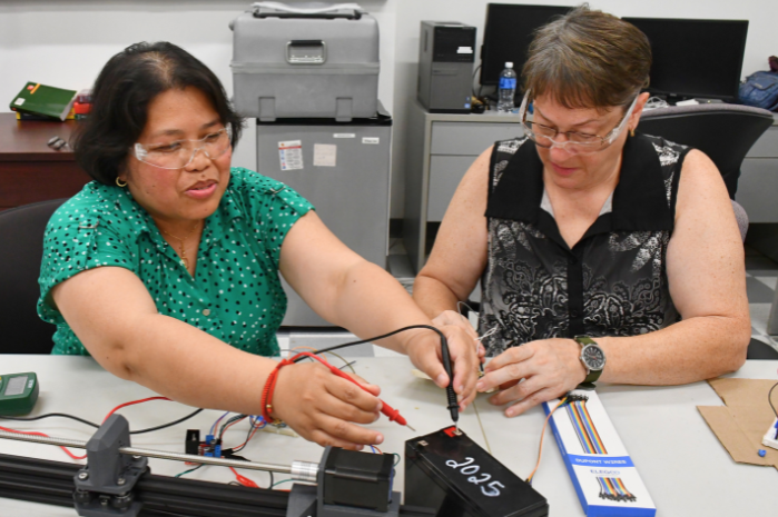 Two teachers working with a piece of equipment