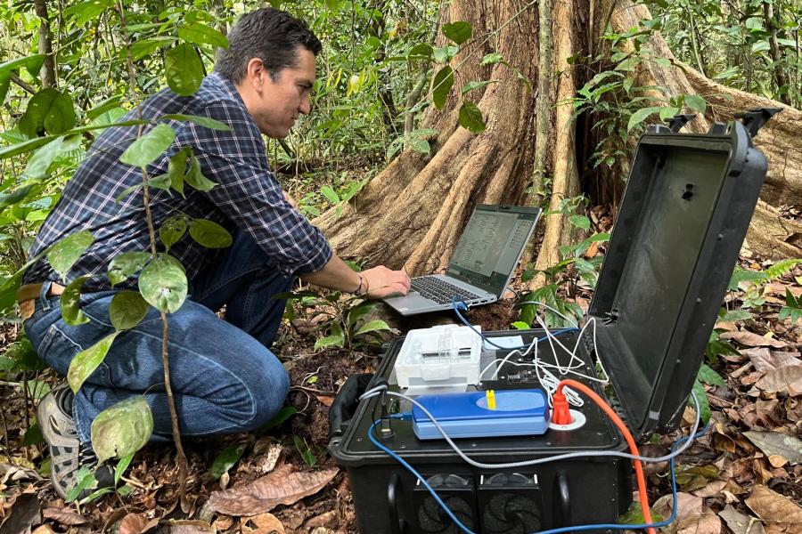 Victor Gonzalez kneeling down on the ground while working on a laptop computer.