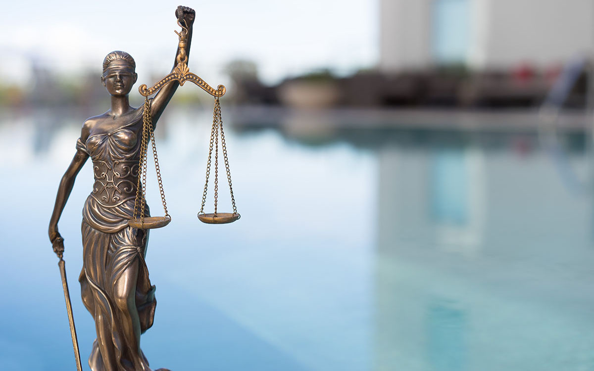 A photo illustration of the blind justice statue near water.