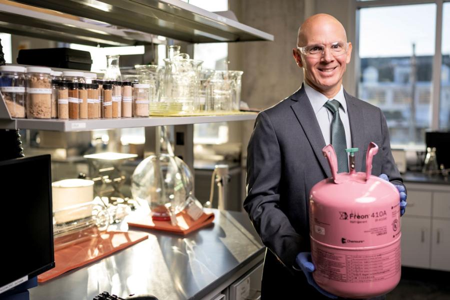 Mark Shiflett smiling holding a tank of refrigerant