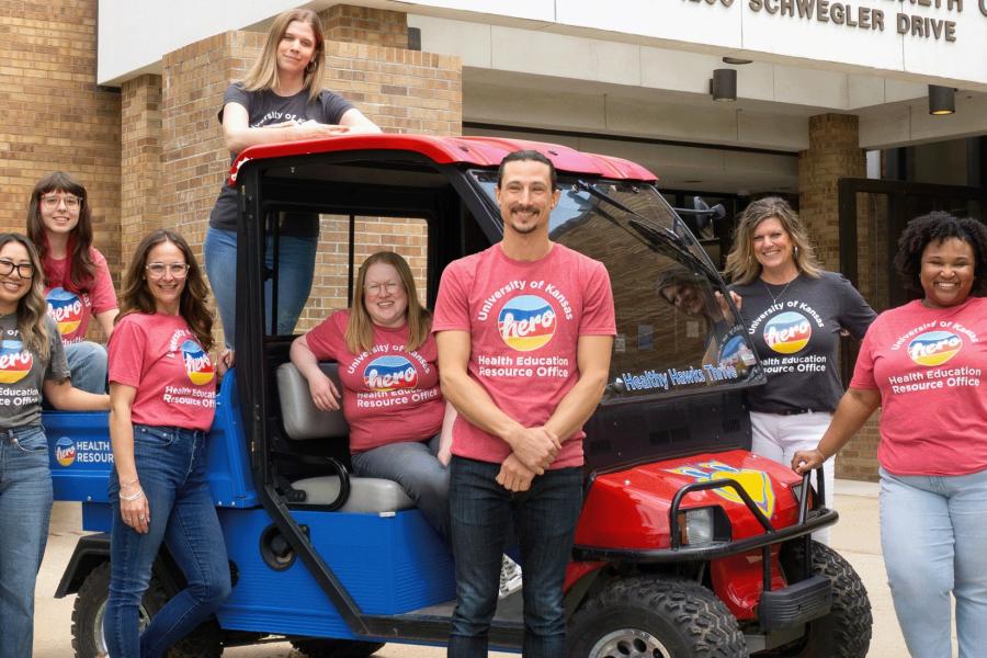 HERO staff posing next to a golf cart in front of the Watkins Health Center