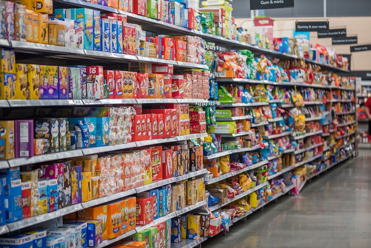 Cereals, crackers and other packaged goods are featured along a supermarket aisle.
