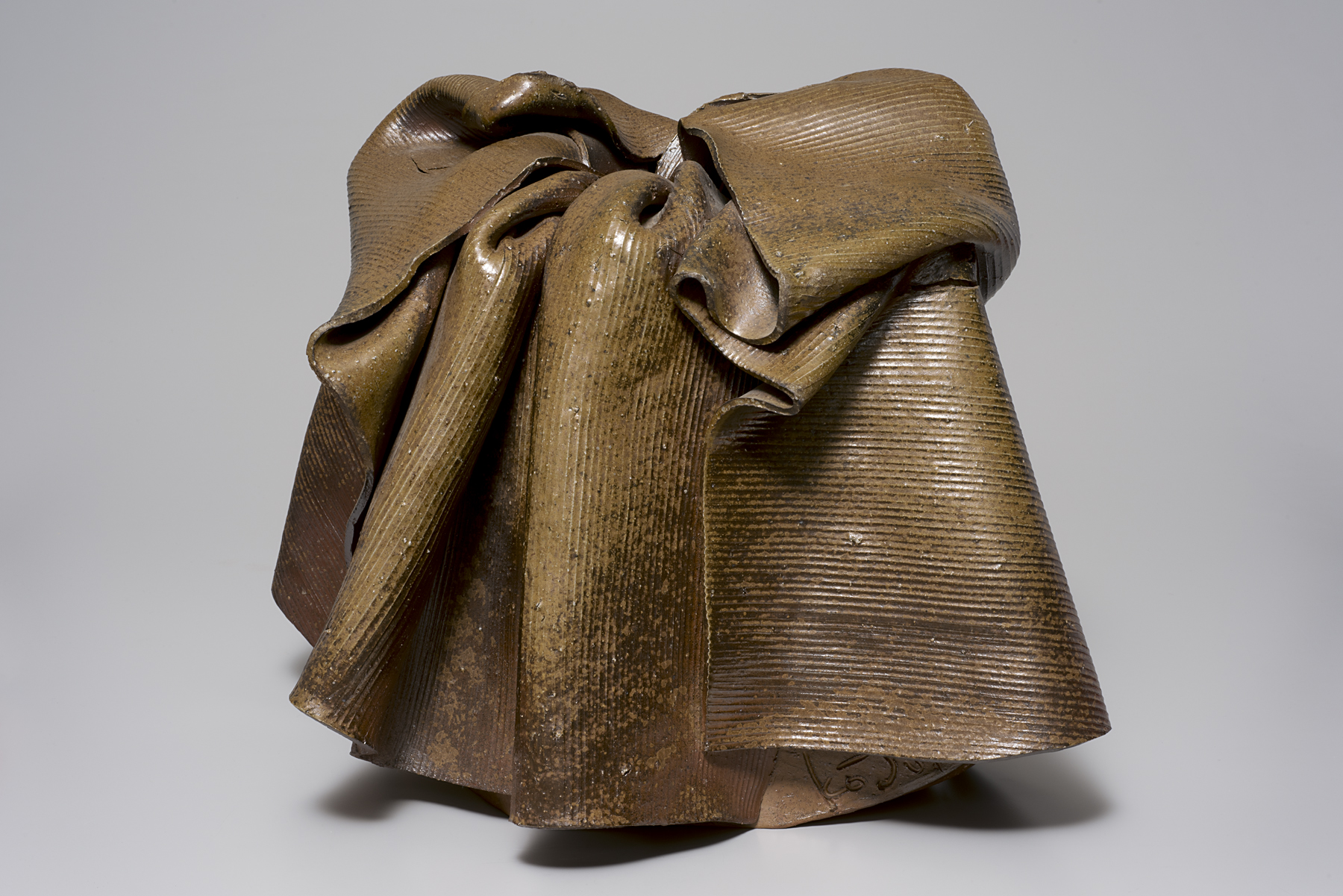 A brown sculpture shaped like a robe with many folds of fabric