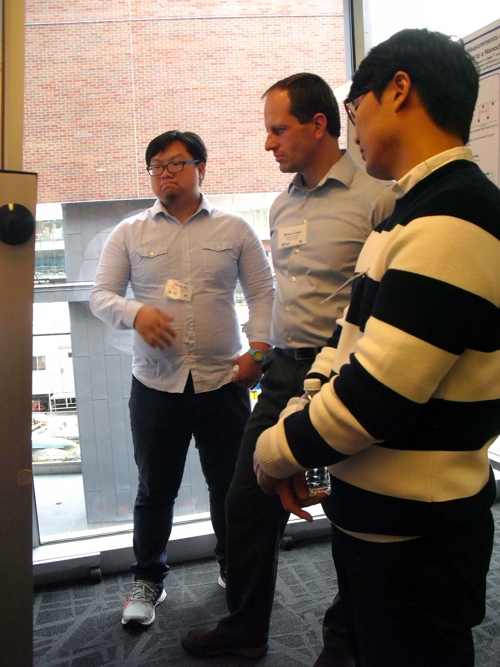 Three individuals displaying keen interest while examining a poster.