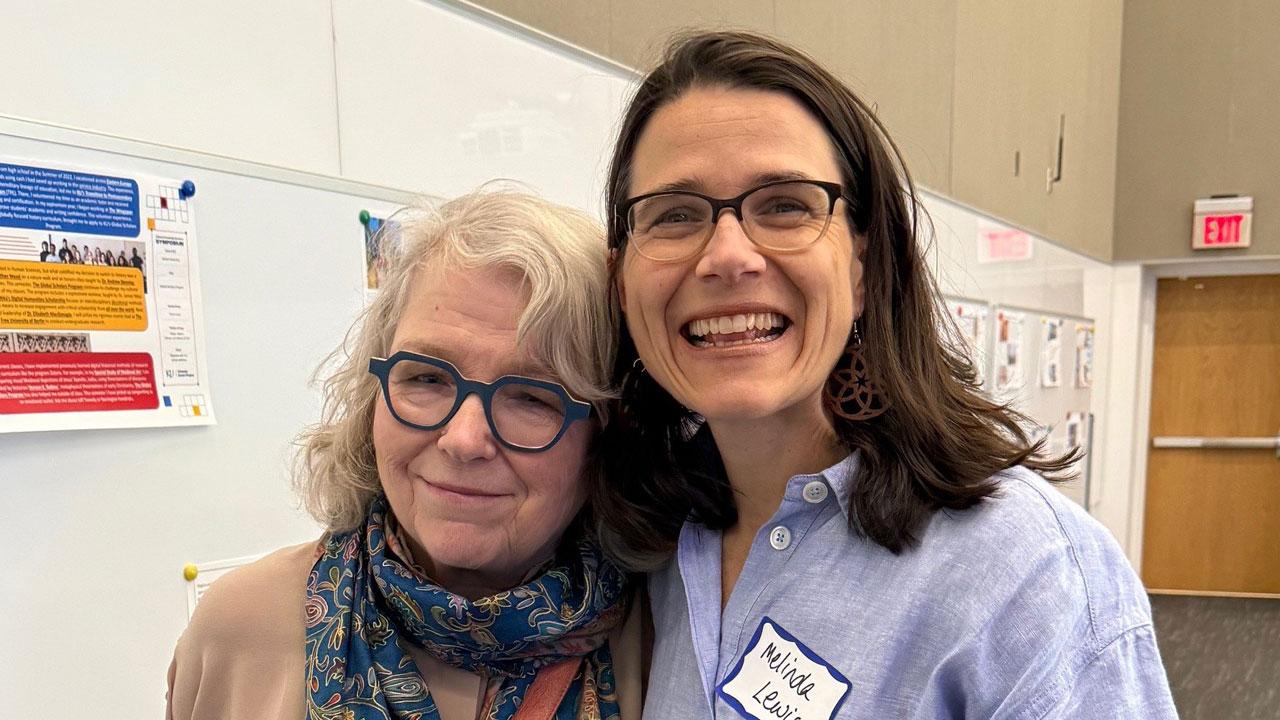 Two women pose in front of whiteboard