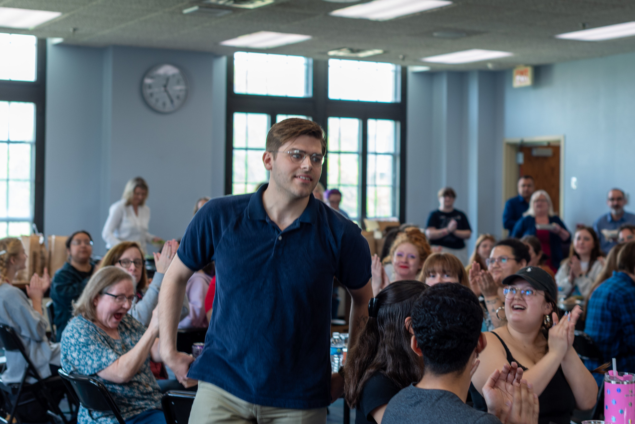 A student walks through an applauding crowd to receive a certificate of excellence.