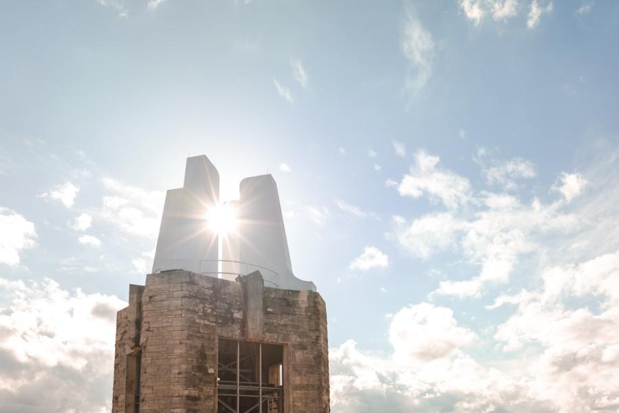 campanile with sun's rays and white clouds against a blue sky