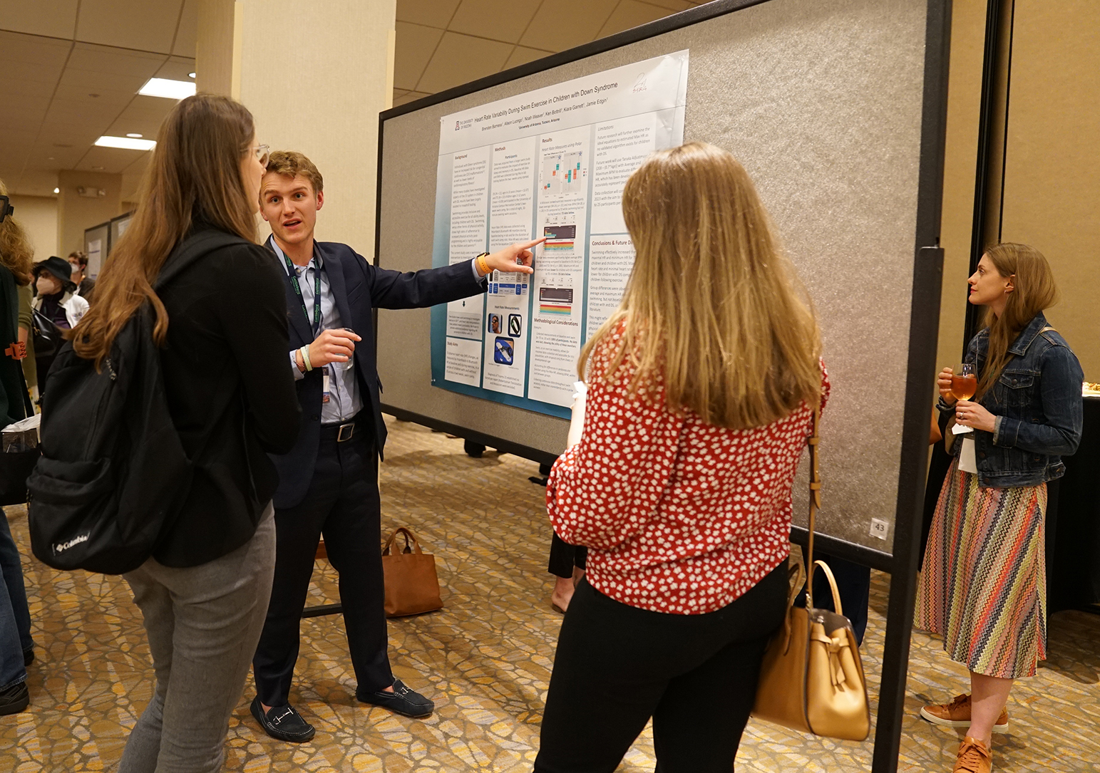 ""A group of people crowd around a poster display at the 2023 Gatlinburg Conference""