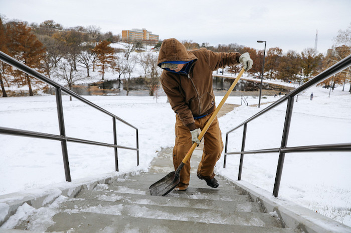 KU grounds employee shoveling snow off stairs