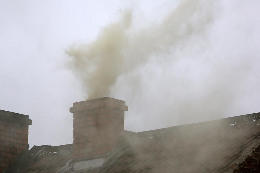 An image of a chimney on a house releasing smoke into the atmosphere.