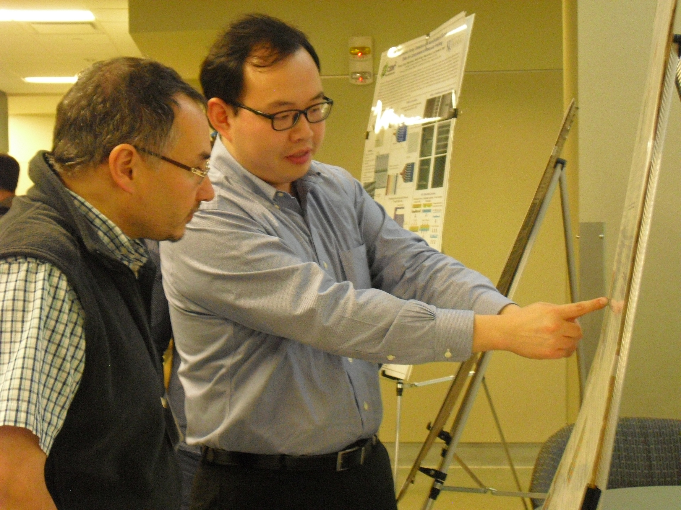 Person pointing to and explaining details on a research poster to another individual.