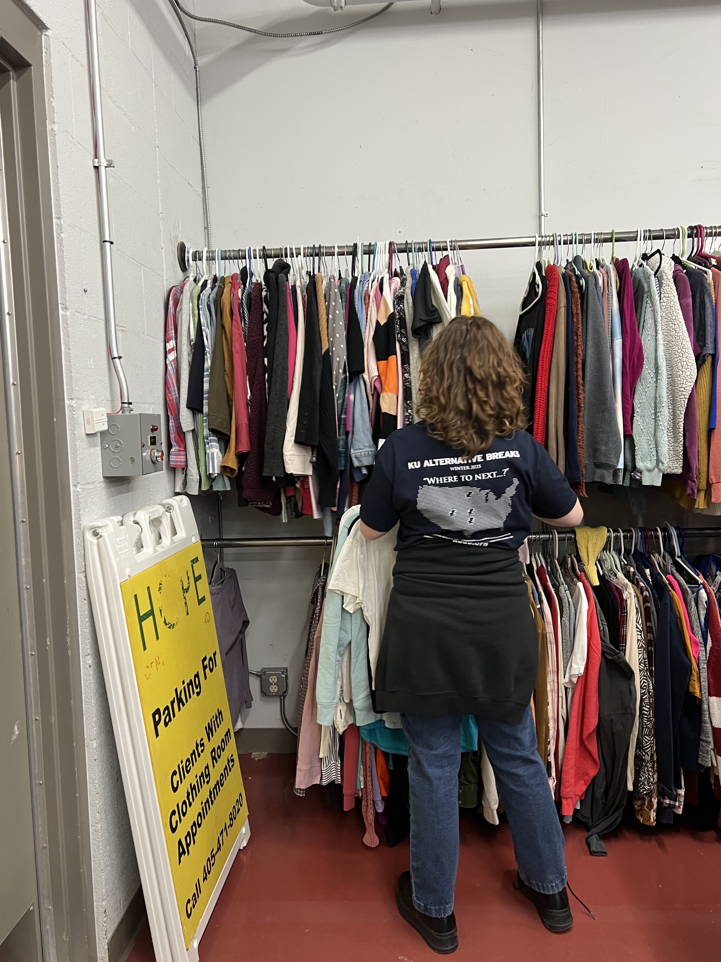 student hanging clothes on racks at the HOPE Center