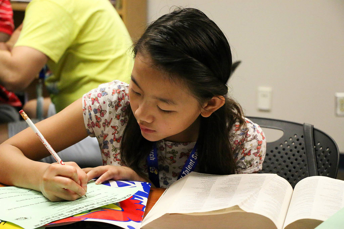 A KU TRIO Talent Search middle schooler looked through college and career books to complete a career exploration scavenger hunt during the Career Horizons Summer Camp.