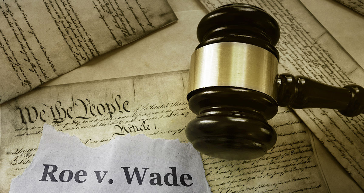 An illustration of a gavel atop the U.S. Constitution and a banner bearing the words Roe v Wade.
