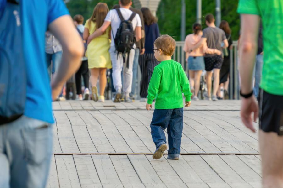 A young child wanders a crowded outdoor space alone