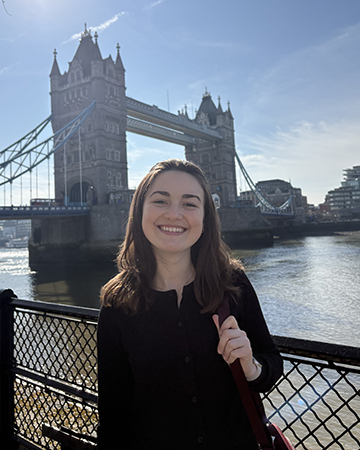 Amelia Knopp stands before the Tower Bridge in London on a sunny day.
