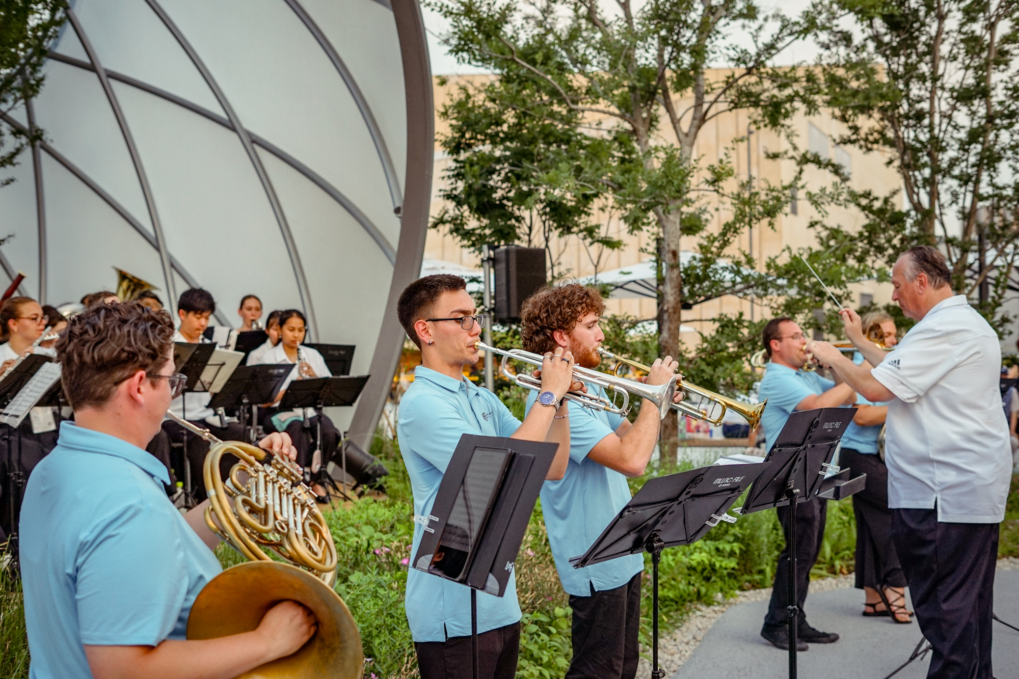 Four musicians in blue shirts playing horns. 