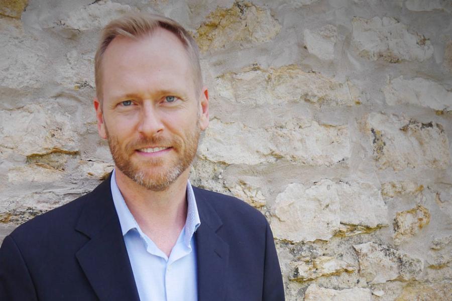 Forrest Pierce, standing in front of a stone wall.