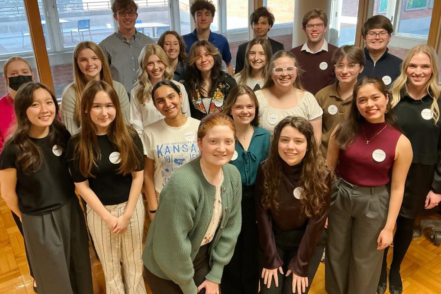 Students pose for group photo by piano.
