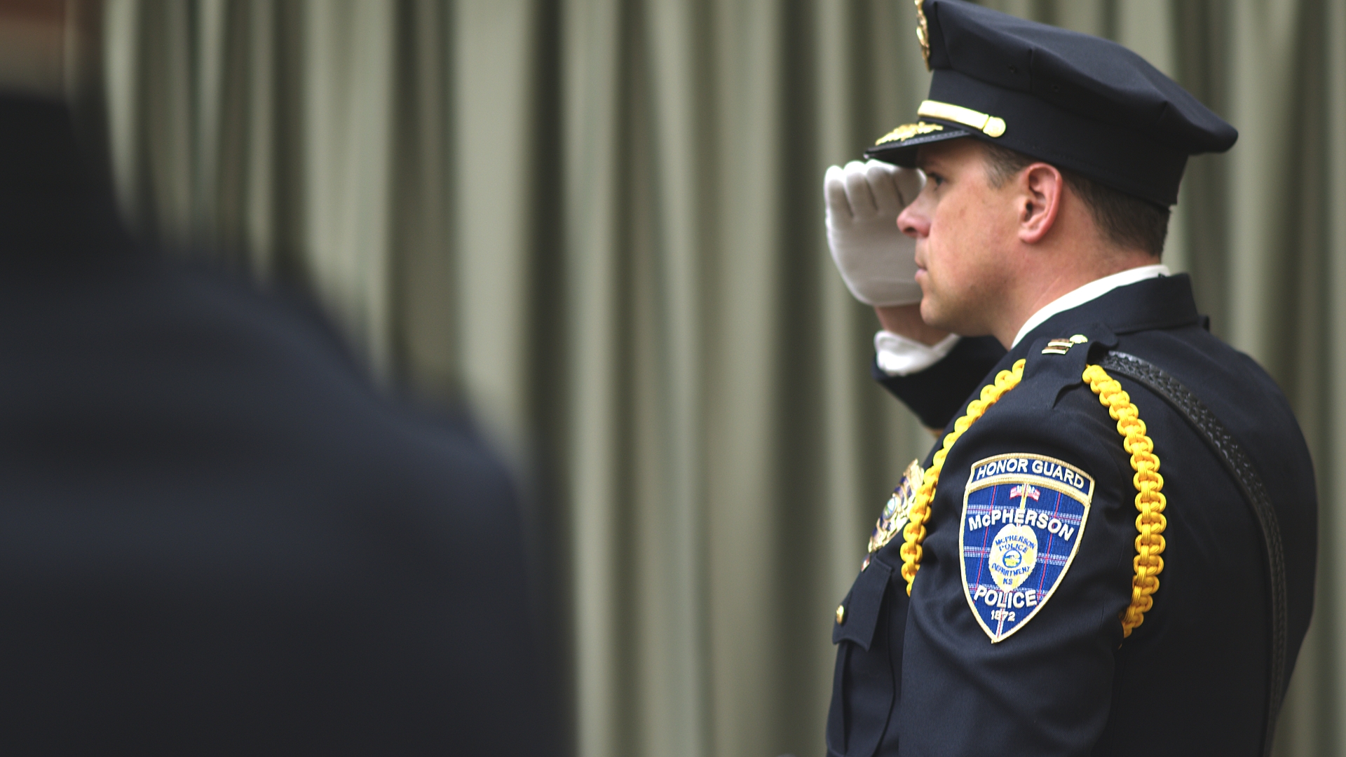 Officer salutes stage at Kansas Law Enforcement Training Center graduation ceremony.