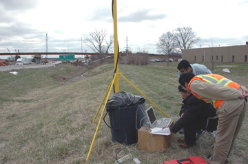 Graduate students working on the project watch as data is downloaded to a computer