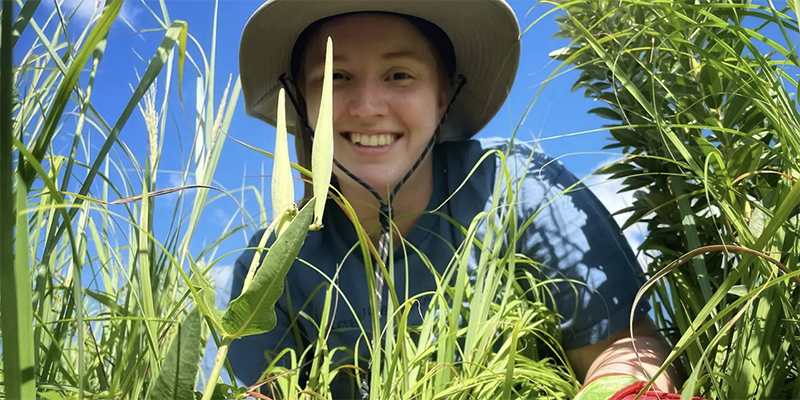 Person wearing hat and facing camera in prairie field