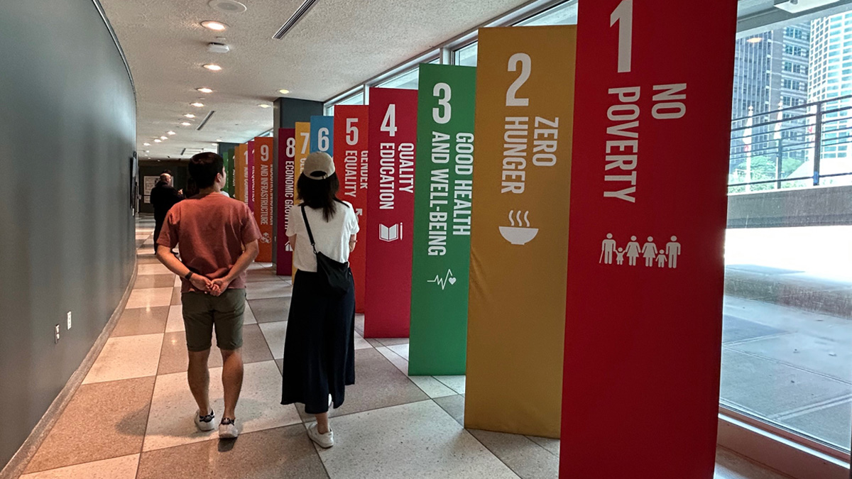 People walk down hallway past multicolored vertical posters