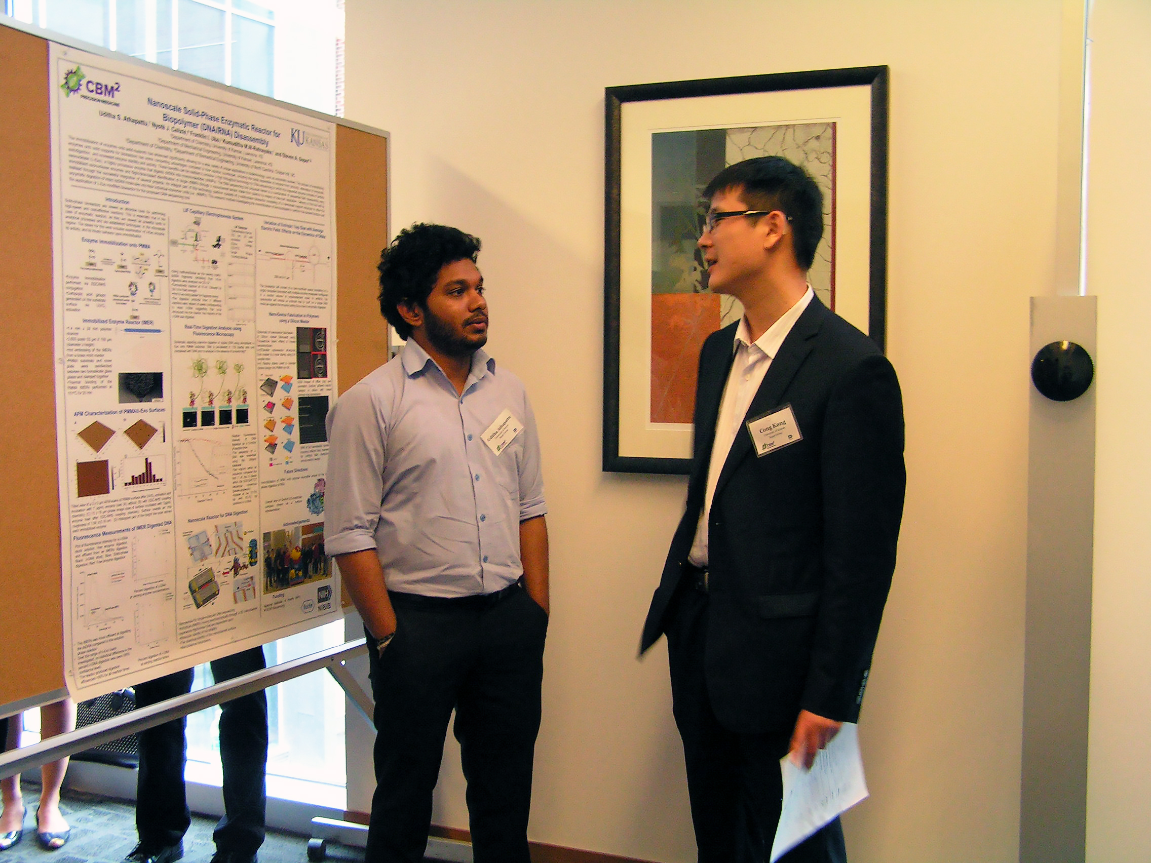 Two people engaged in conversation in front of a displayed poster.