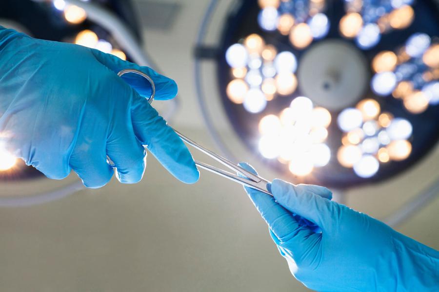 Medical personnel exchanging surgical tools in OR.