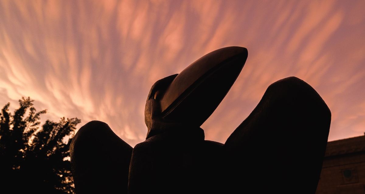 Jayhawk sculpture silhouette against colorful sky