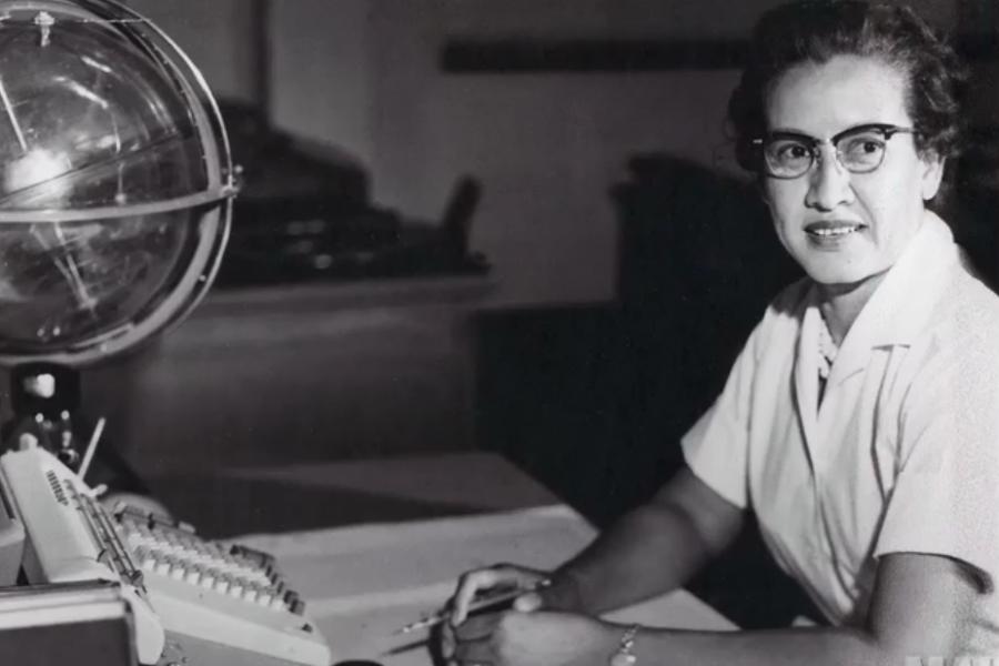 An archival photo of Katherine Johnson working at her desk at NASA.