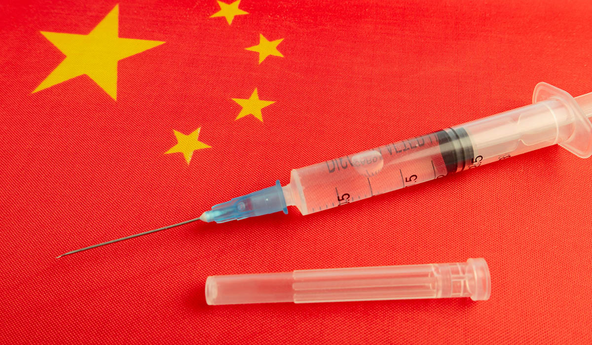 Chinese flag with vaccine needles sitting on top of it.