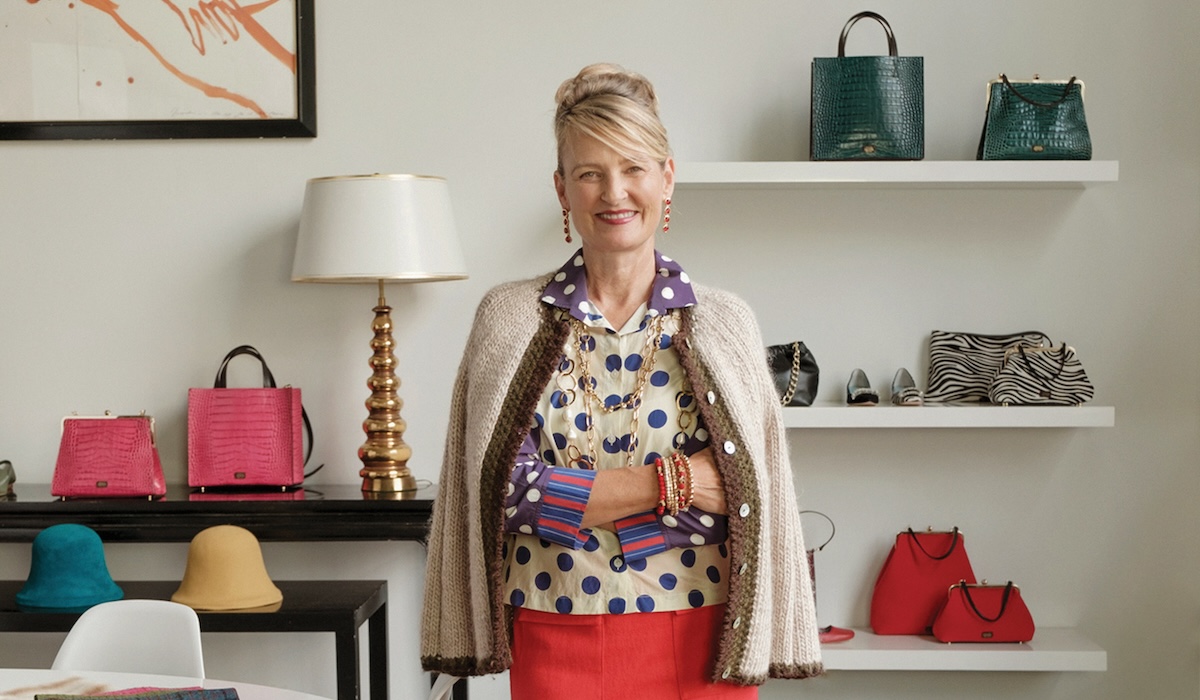 Elyce Arons with handbags on shelf behind her