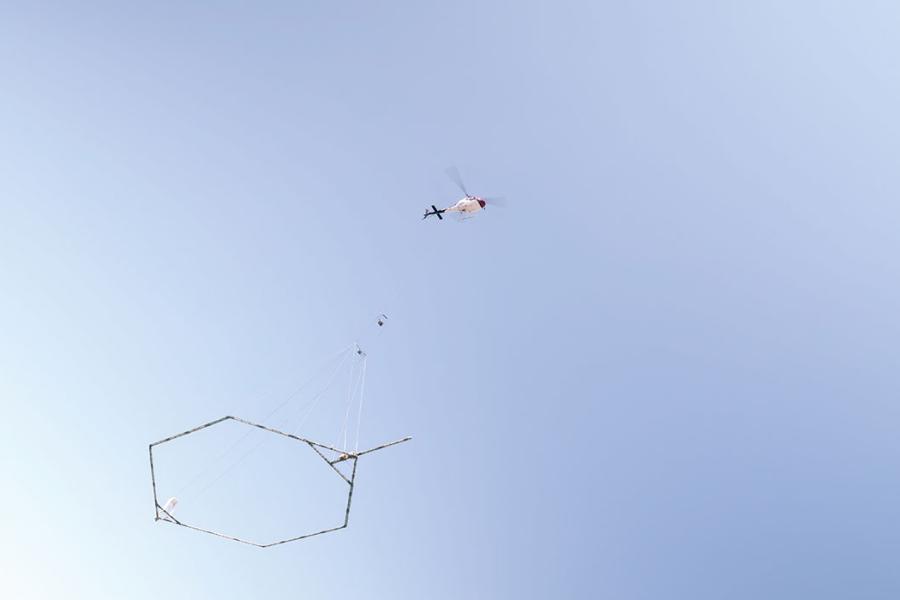 Airborne electromagnetic surveying include plane with hanging frame in blue sky