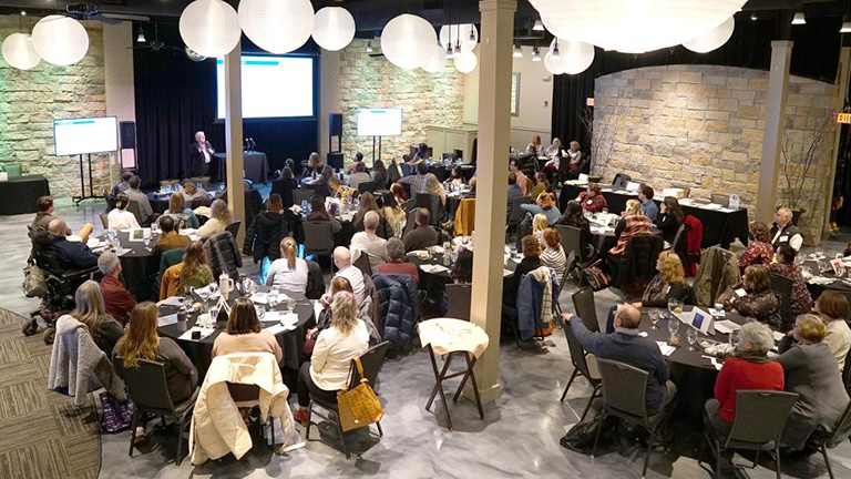 Participants at the collaboratory viewed from above, with large white lantern lights at the top.