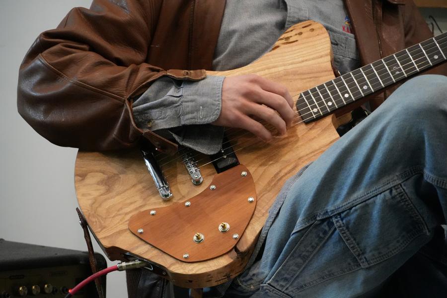 A group of students jump while holding custom electric guitars.